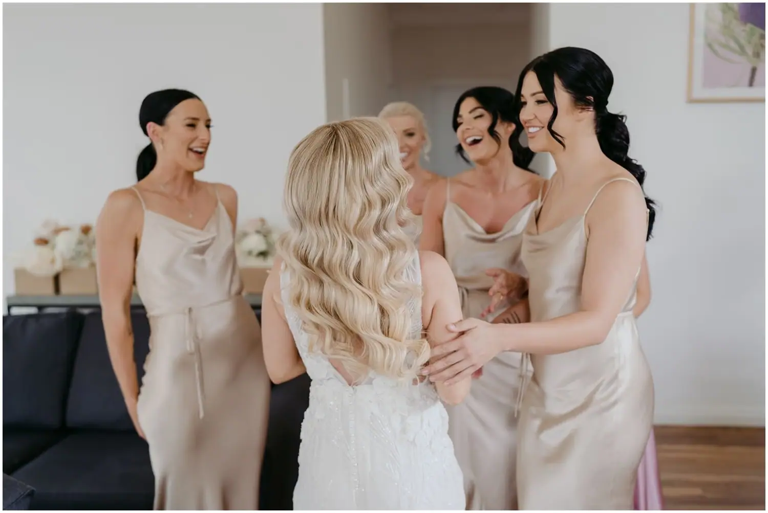 Bride and friends laughing together in pale dresses indoors