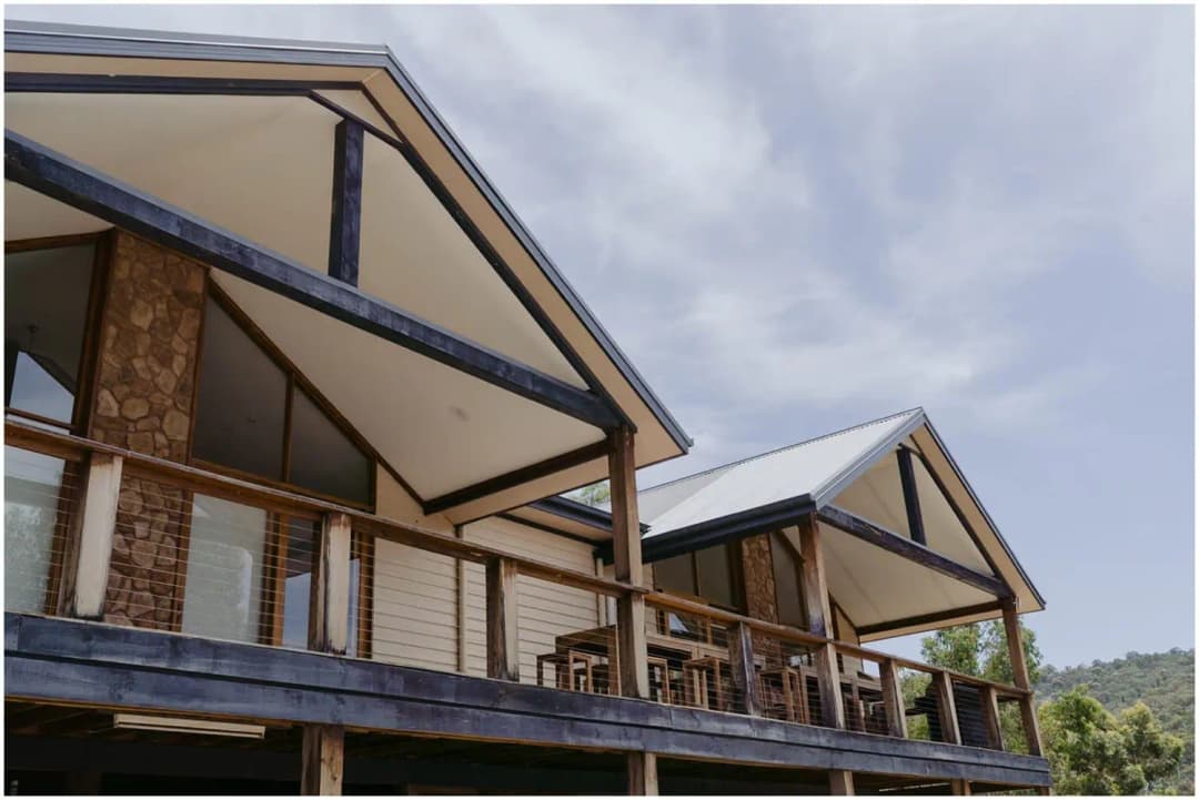 Timber cabins with stone chimneys and covered verandas beneath a cloudy sky