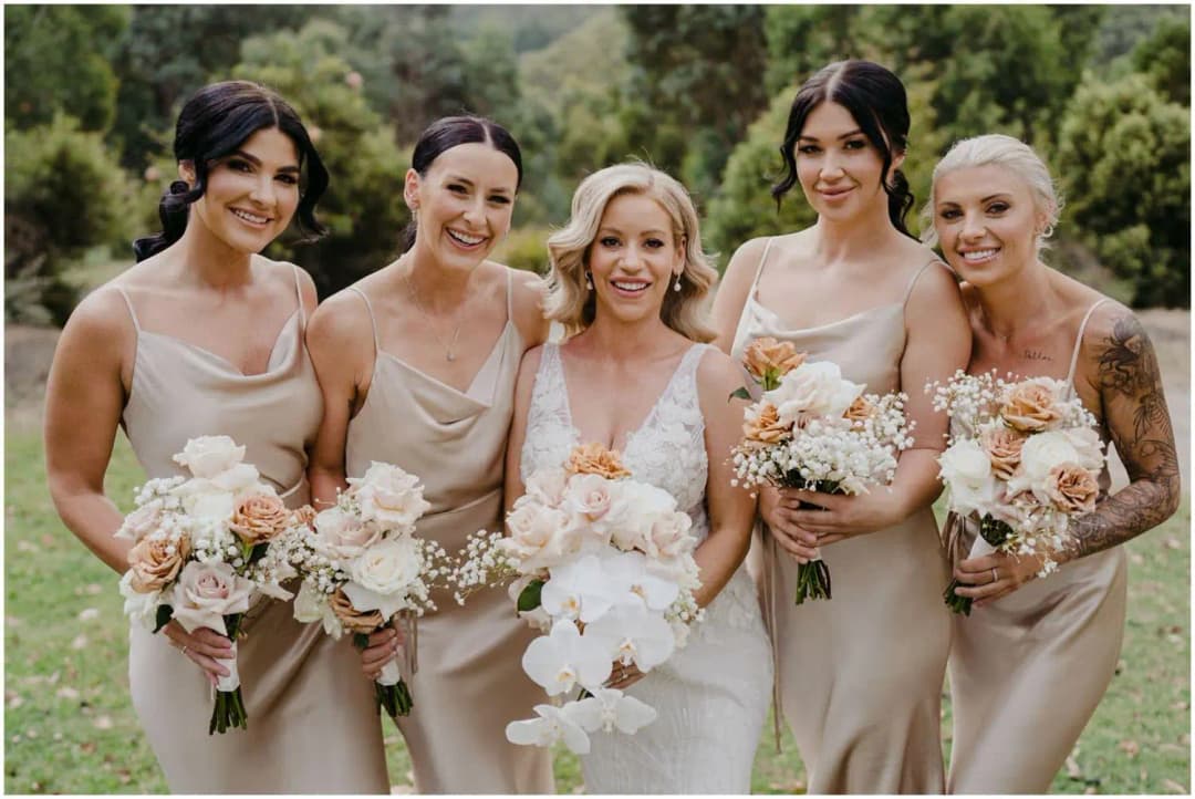 Bride and four bridesmaids posing outdoors with pale bouquets