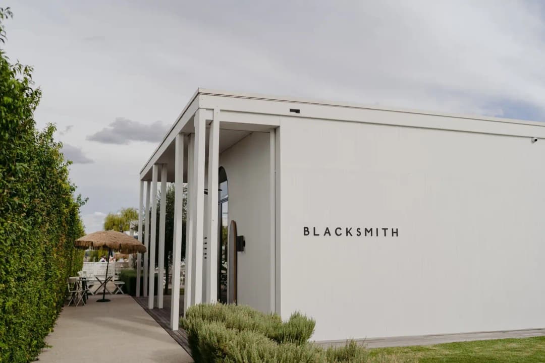 White venue building with Blacksmith lettering beside a hedge