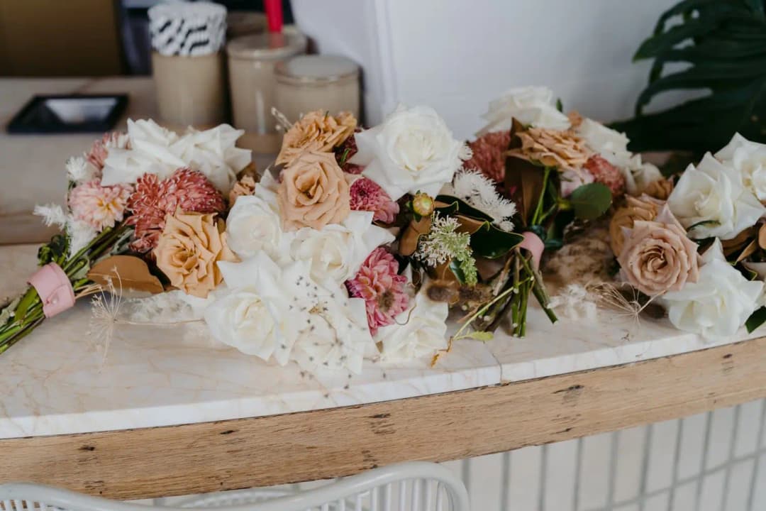 Peach and white wedding bouquets resting on a wooden counter