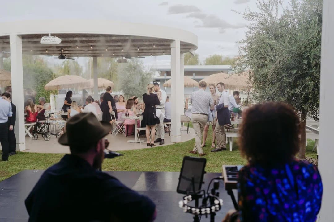 Musicians in the foreground facing guests gathered in an outdoor reception garden