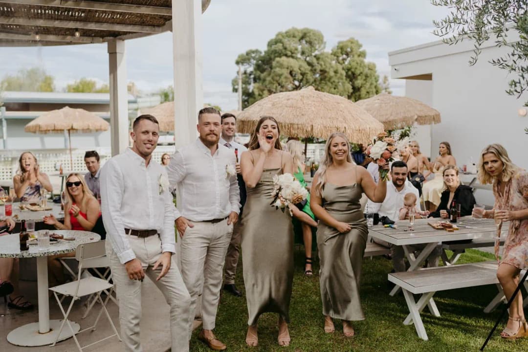 Wedding party cheering as they walk between seated reception guests