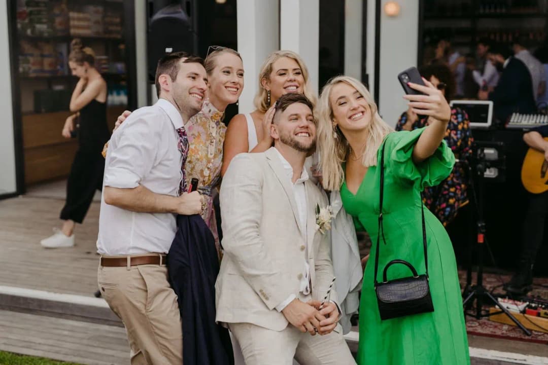 Groom posing with guests for a selfie beside the reception entrance