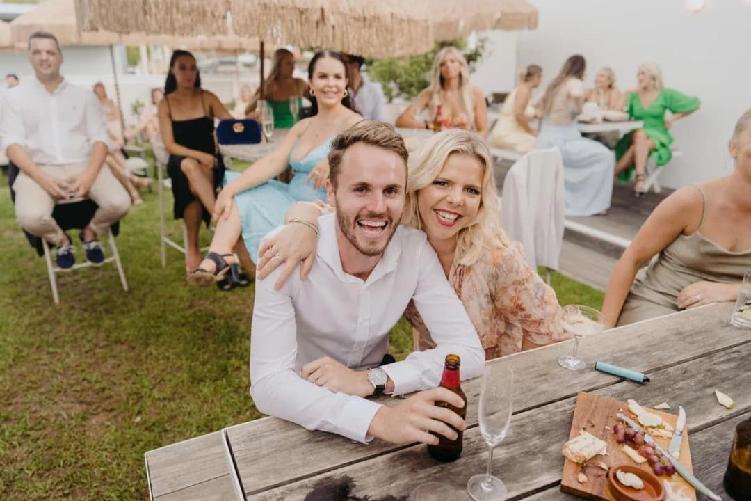 Smiling guests seated together at a wooden picnic table