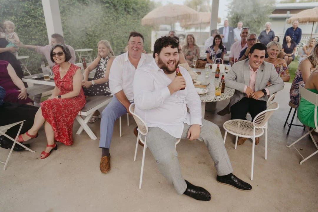Wedding guests laughing while seated in the outdoor reception garden