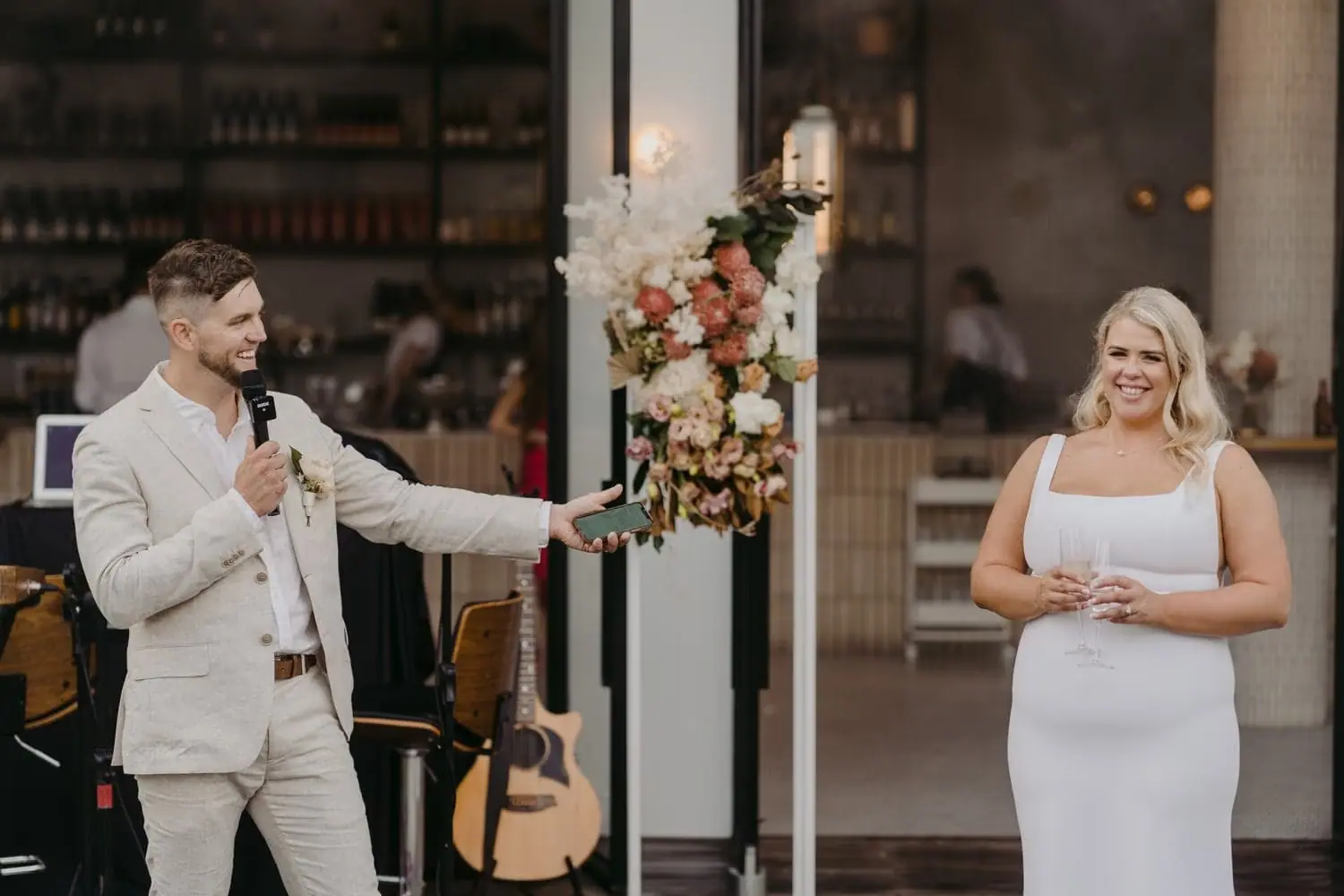 Groom speaking into a microphone beside the smiling bride