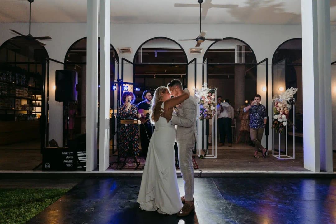 Bride and groom dancing outside the illuminated reception building at night