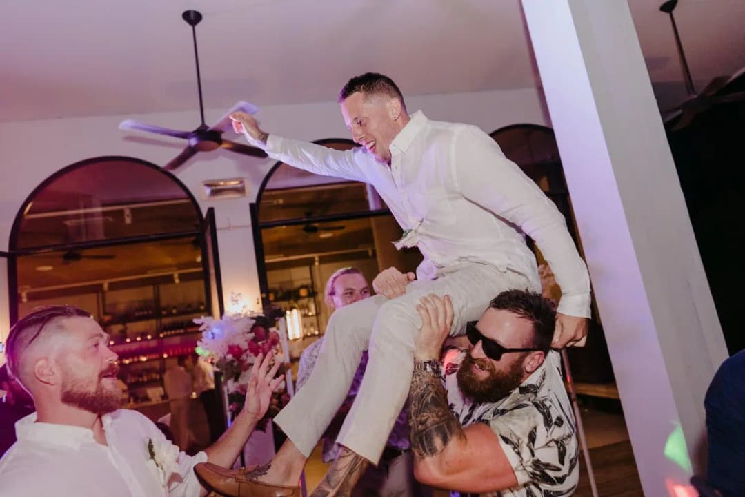 Guest raising a drink while sitting on another guest's shoulders