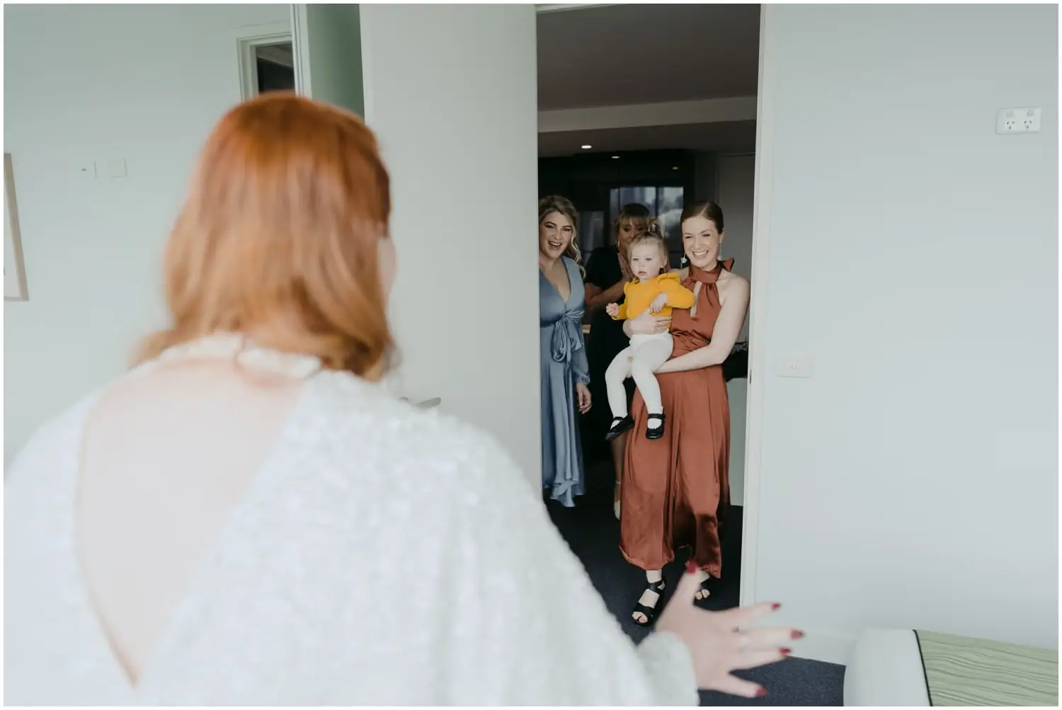 Bride facing friends and a young child in an open doorway