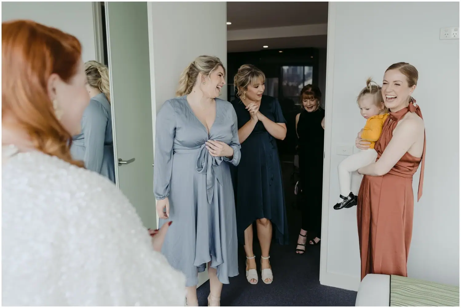 Friends smiling at the bride, with one woman holding a young child
