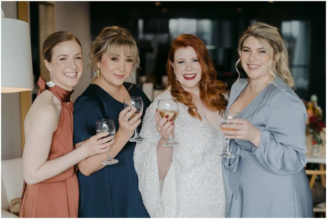 Bride and three friends smiling together with glasses of wine