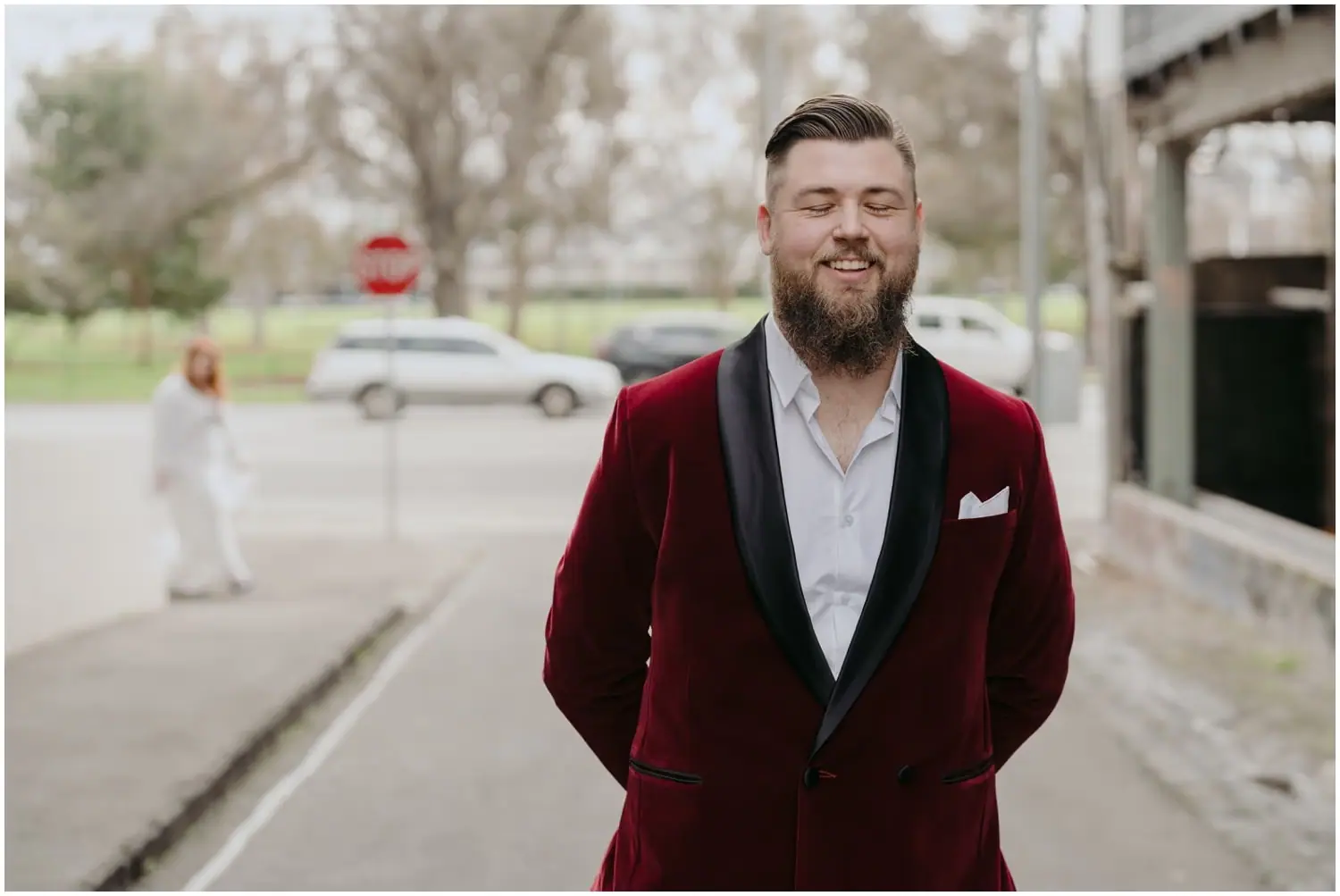 Groom smiling with closed eyes as the bride approaches from behind