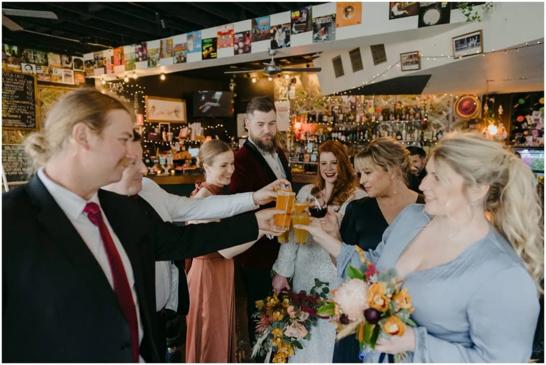 Wedding party clinking glasses together in a decorated pub