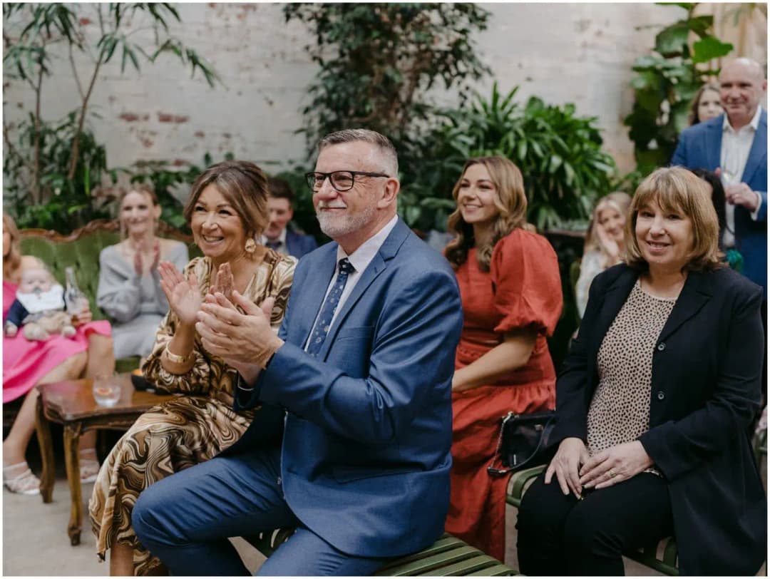 Guests applauding from their ceremony seats amid greenery