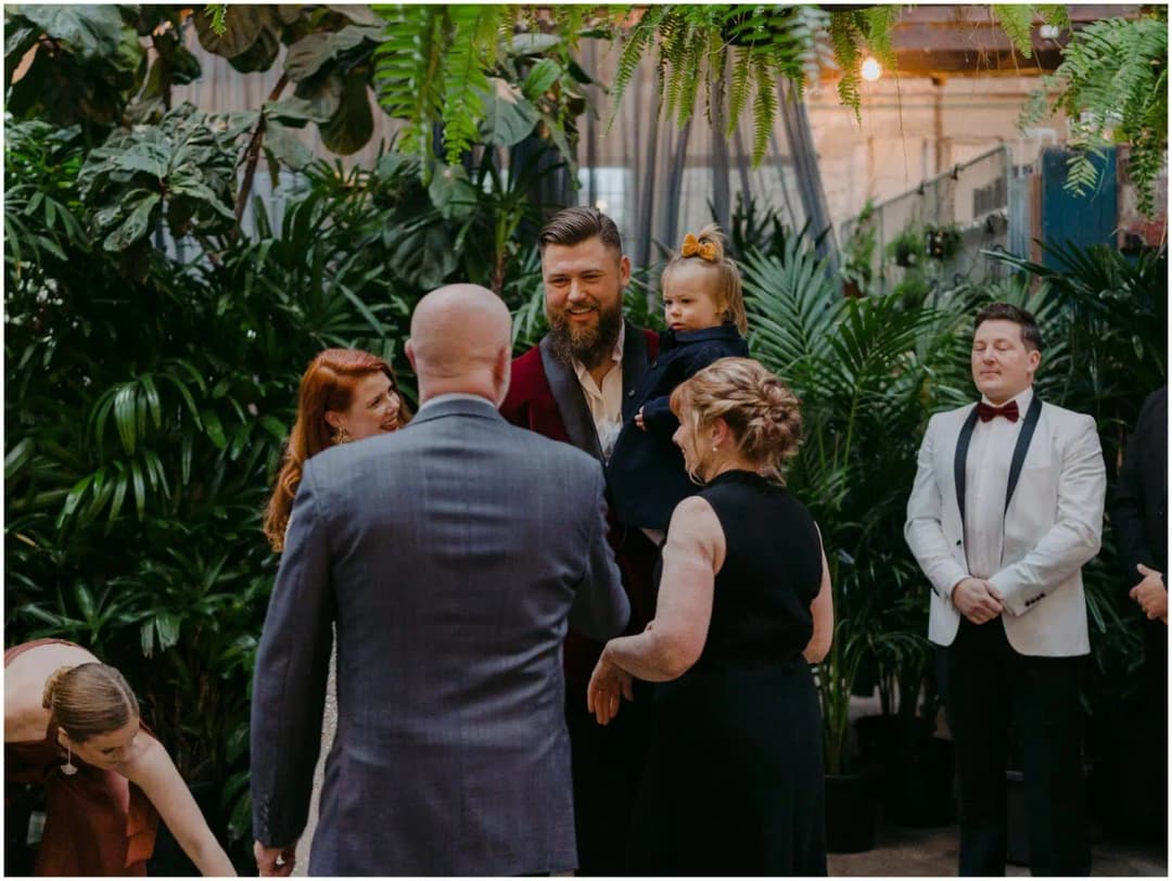 Wedding party gathered at the front of the ceremony with the groom holding a child