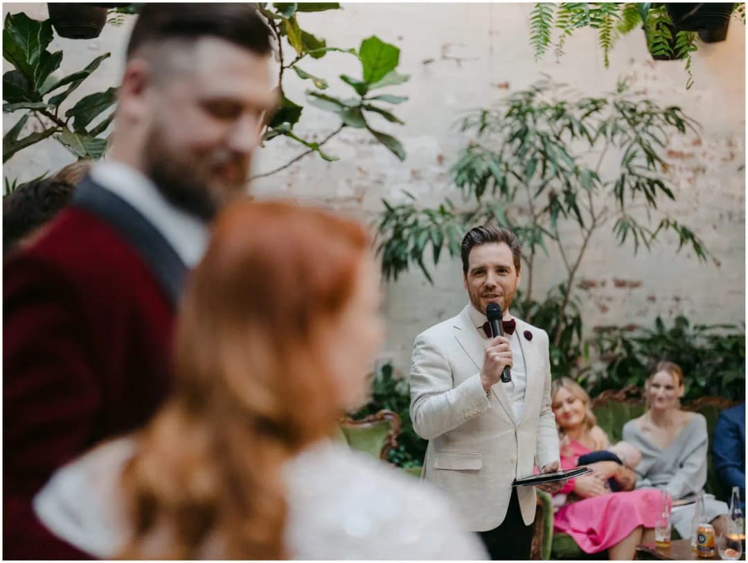Celebrant speaking into a microphone while the bride and groom stand in the foreground