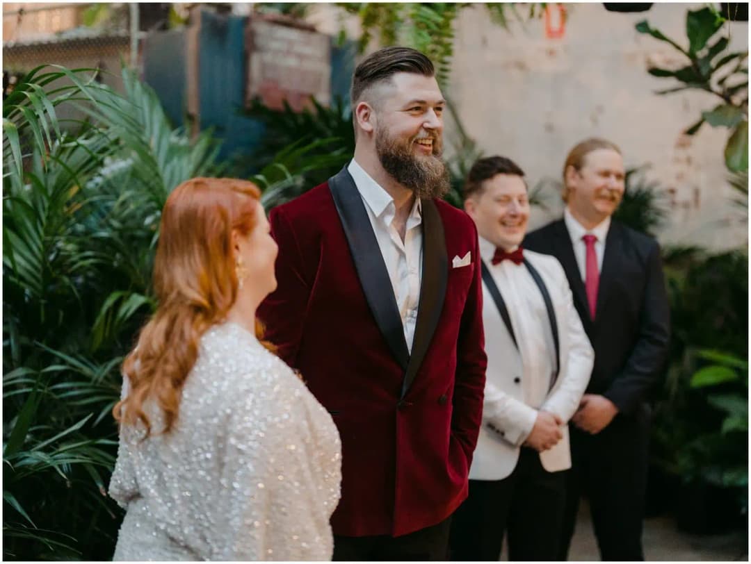 Bride and groom smiling during the ceremony with friends behind them