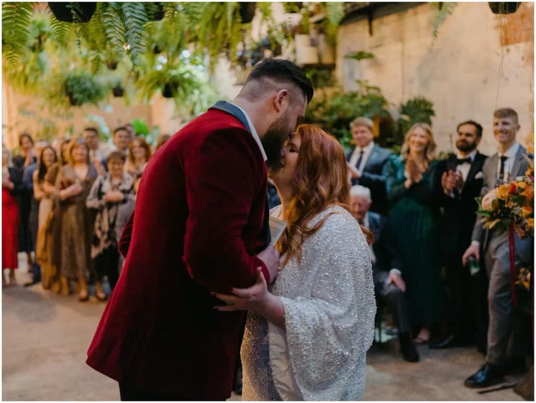 Groom leaning toward the laughing bride while guests watch