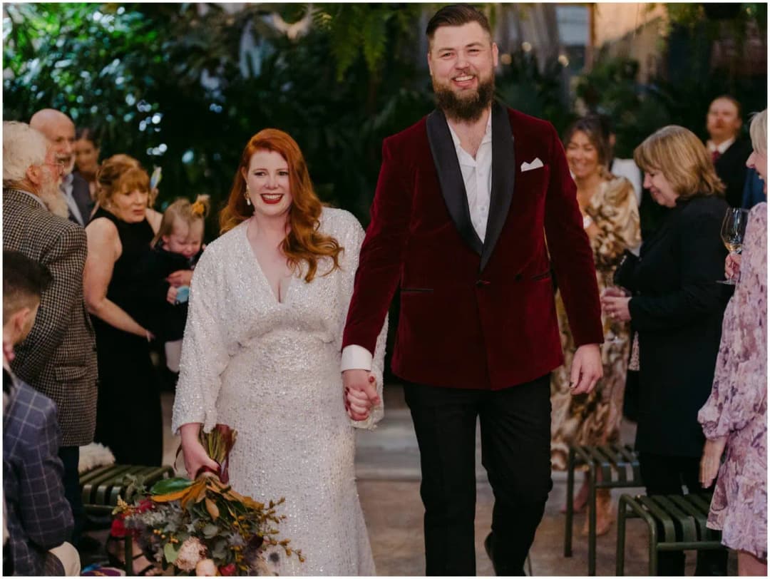 Bride and groom holding hands and walking past applauding guests