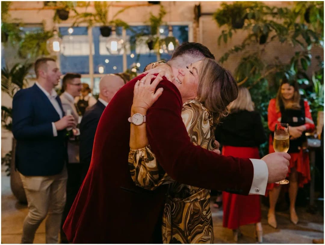 Groom hugging a guest while holding a drink after the ceremony
