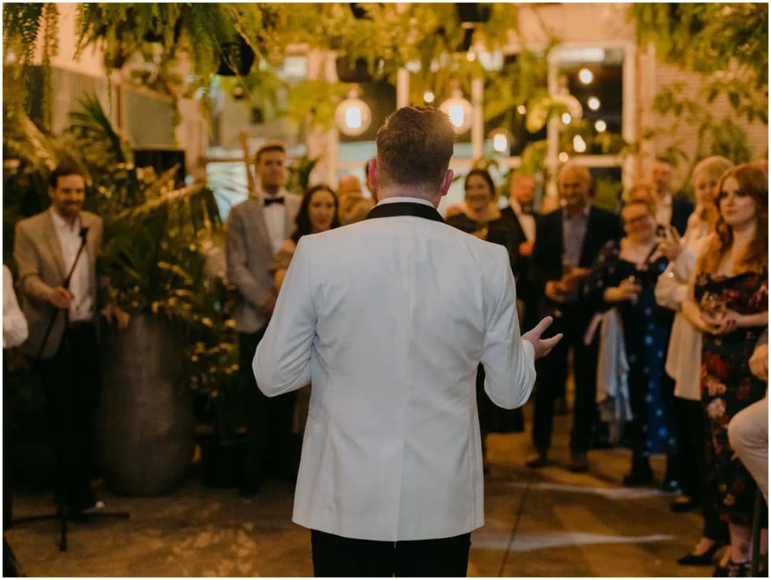 View from behind a man addressing gathered guests with a microphone
