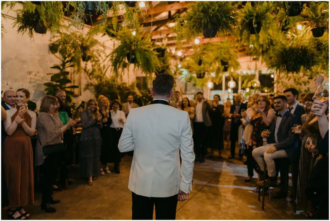 Guests gathered in a circle around a speaker beneath hanging greenery