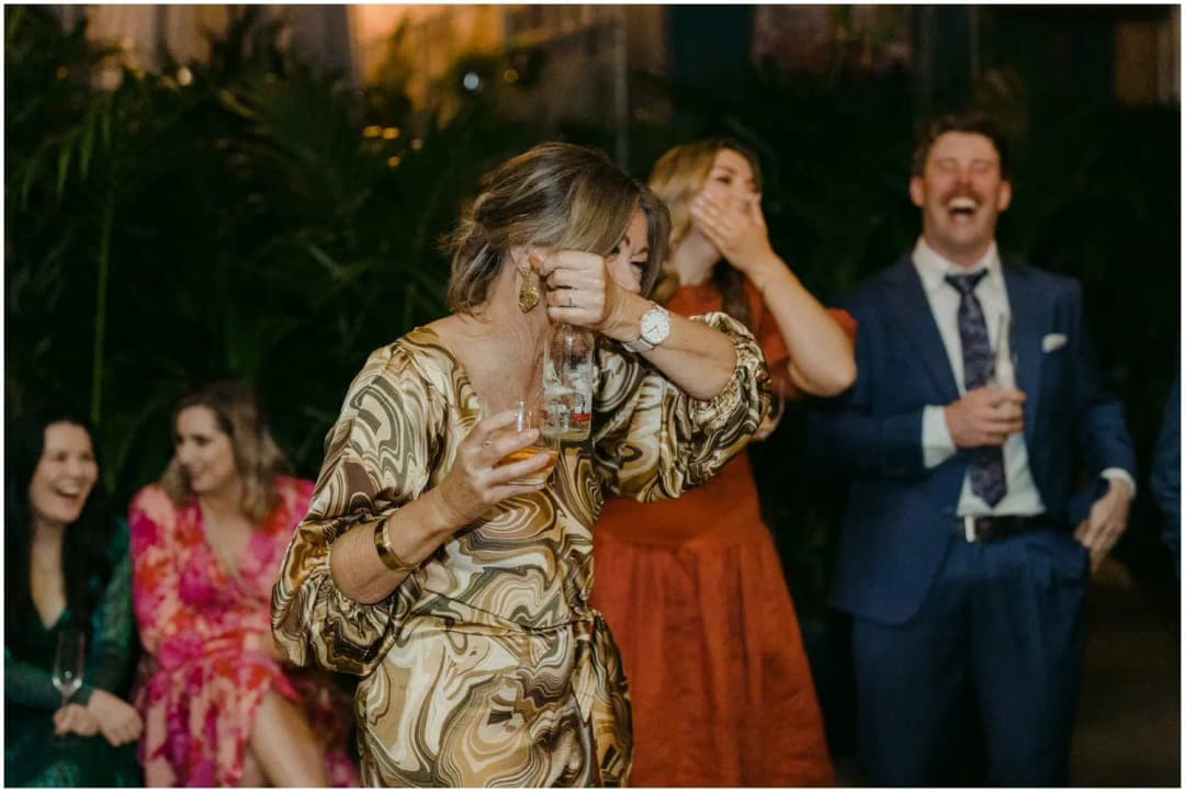 Woman covering her face while nearby guests laugh during a speech