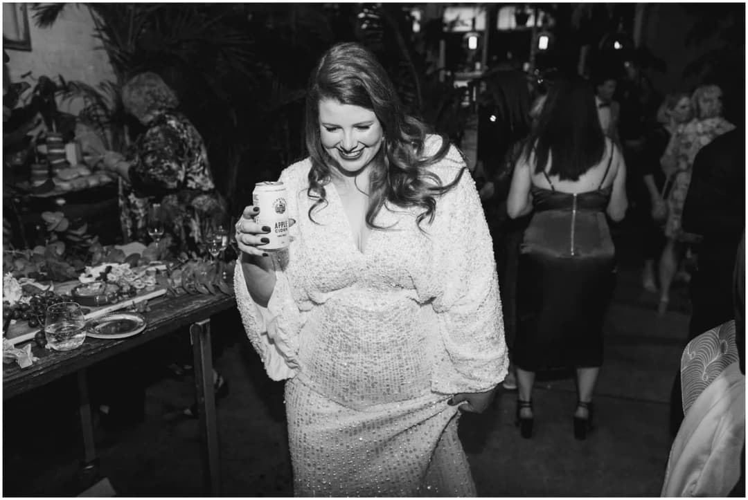 Black-and-white photograph of the bride smiling while holding a drink