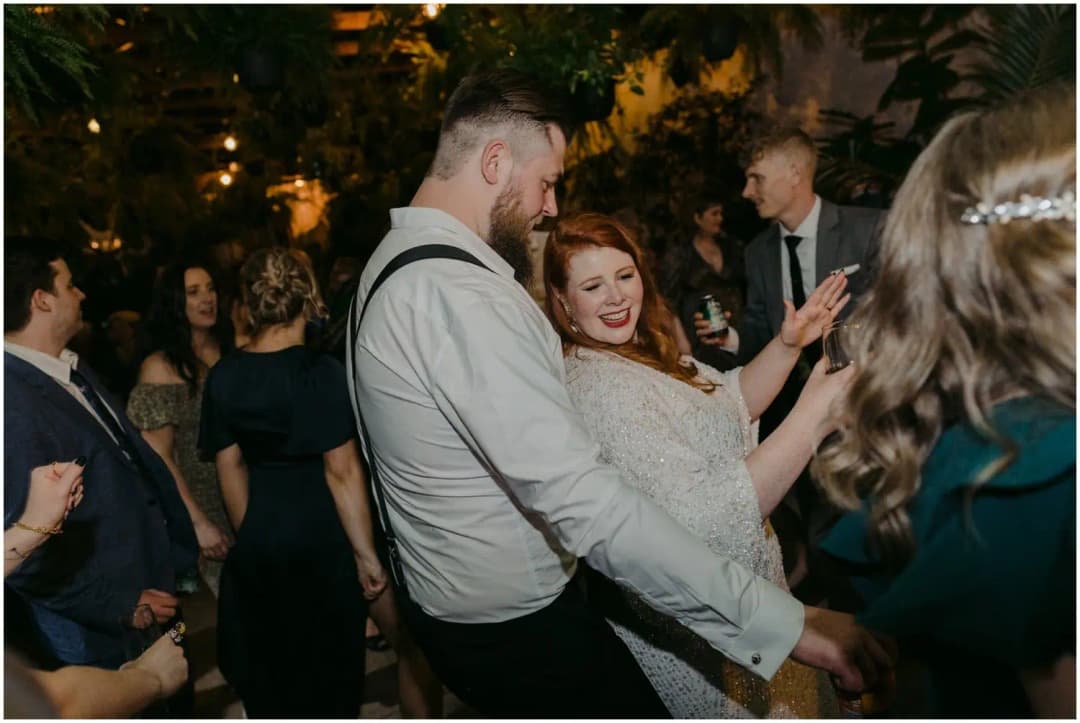 Bride and groom smiling together while dancing among guests