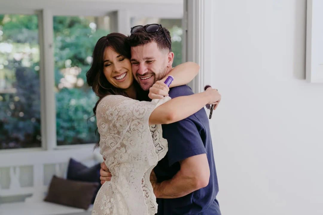 Bride and groom embracing and smiling while getting ready indoors