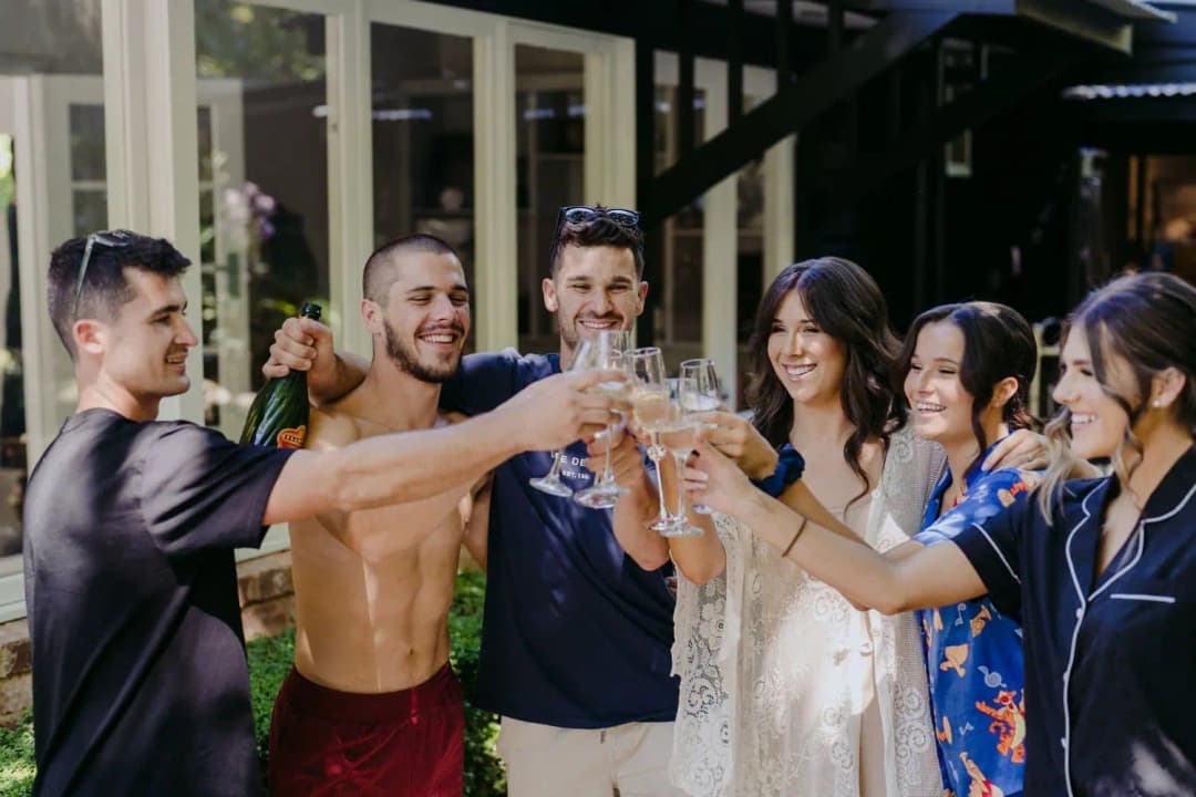 Wedding party raising their glasses together outside a cabin