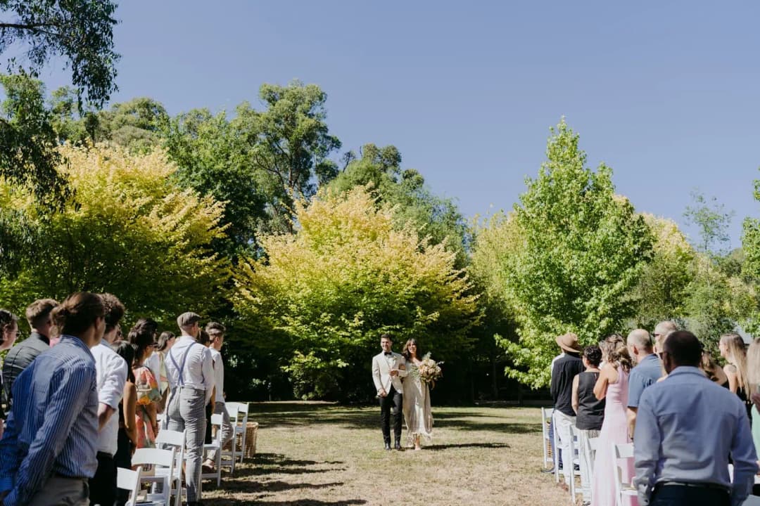 Bride and groom walking toward the ceremony through rows of standing guests