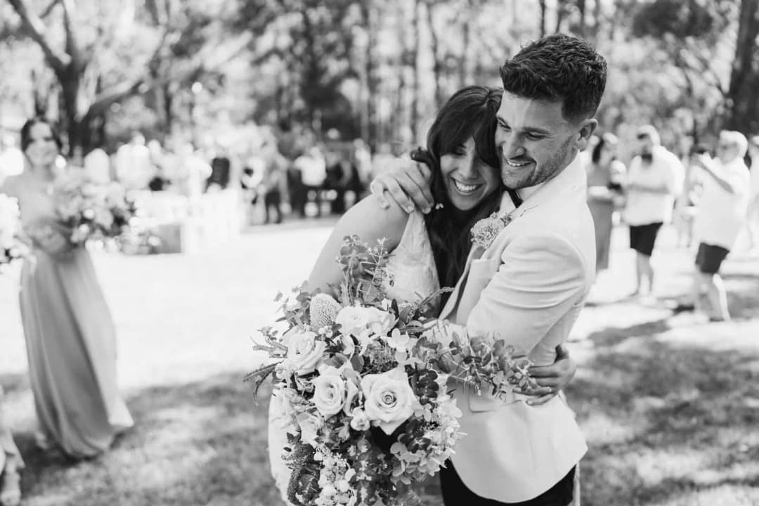 Black and white photograph of the bride and groom embracing with a bouquet