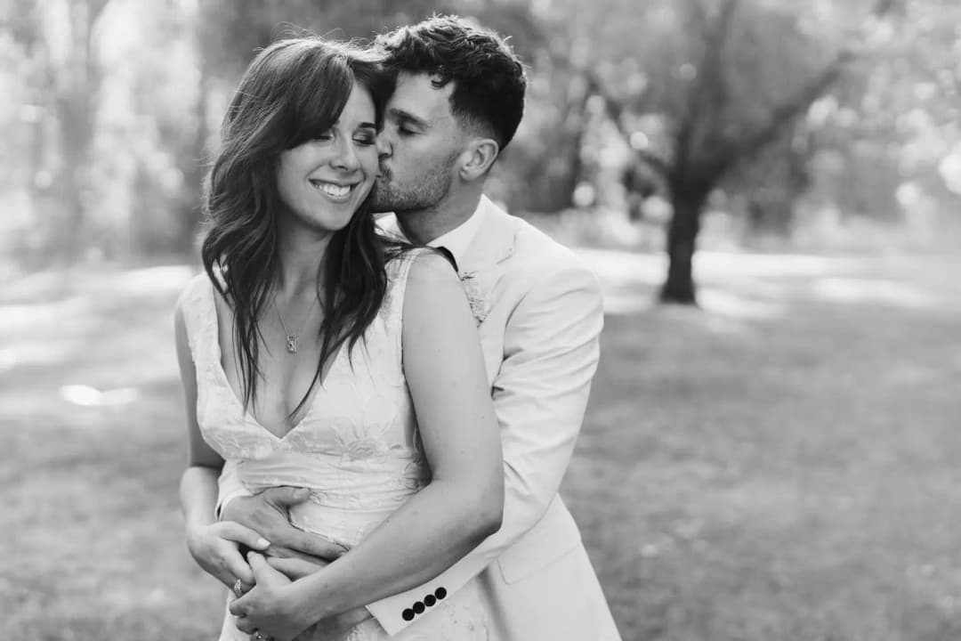 Black and white photograph of the groom embracing the smiling bride from behind