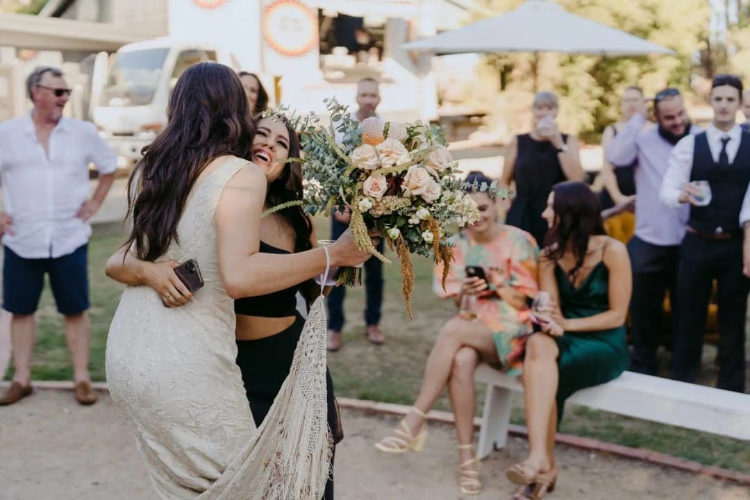 Bride hugging a guest outside the reception barn