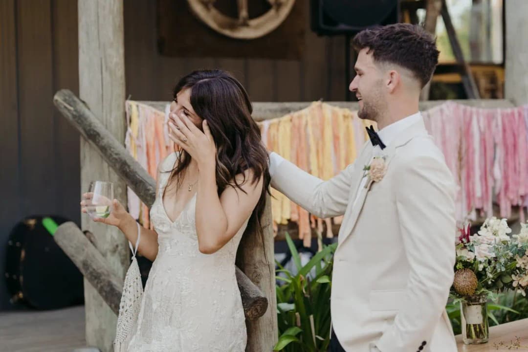 Bride wiping her eye as the groom rests his hand on her shoulder