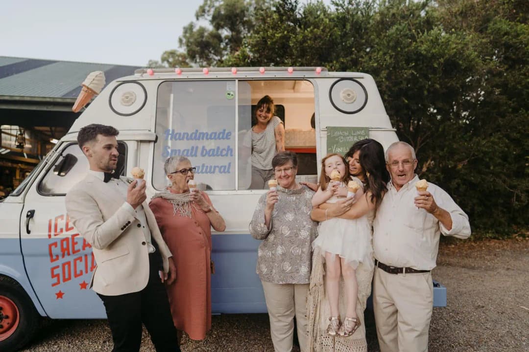 Couple and guests smiling with ice cream cones beside an ice cream van