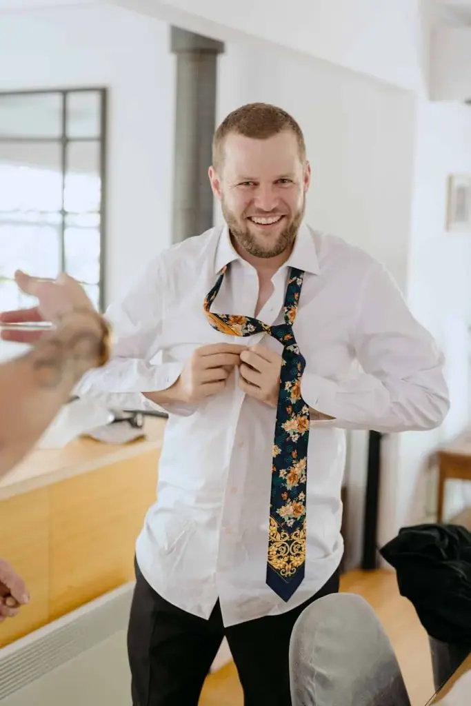 Groom fastening his shirt while getting ready