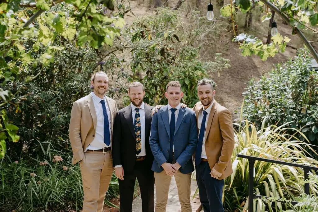 Groom and groomsmen posing in a leafy garden
