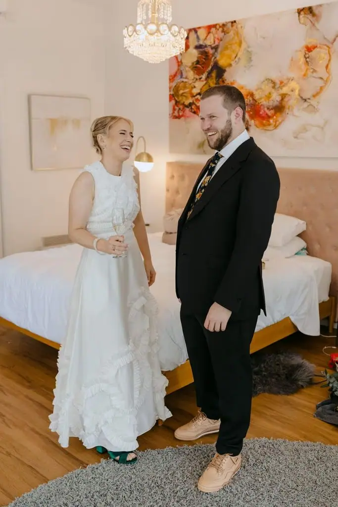 Couple laughing together beside a bed