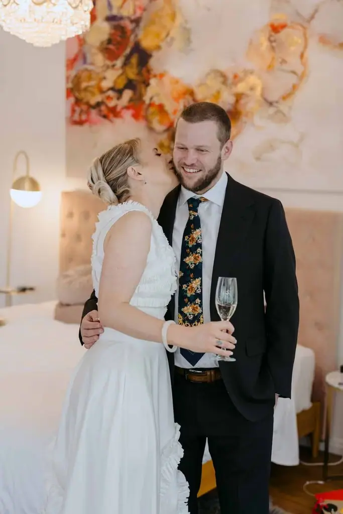 Bride kissing the groom's cheek while holding a glass