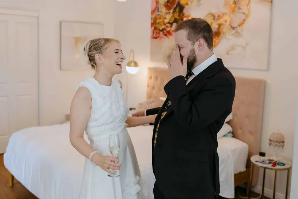 Groom laughing as the bride watches
