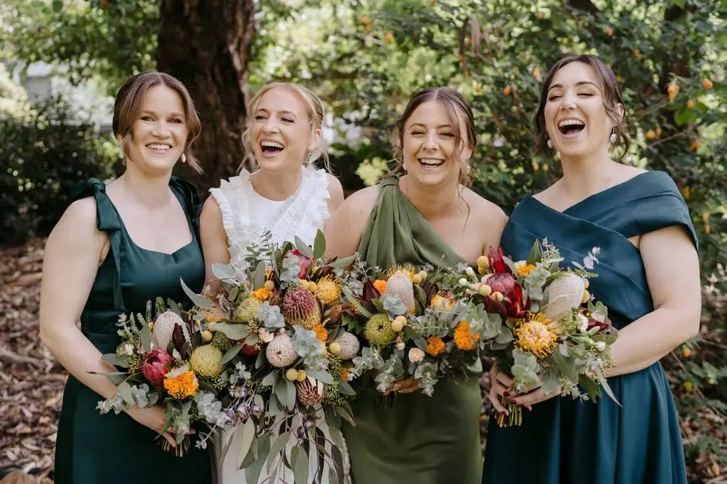 Bride and bridesmaids laughing with their bouquets