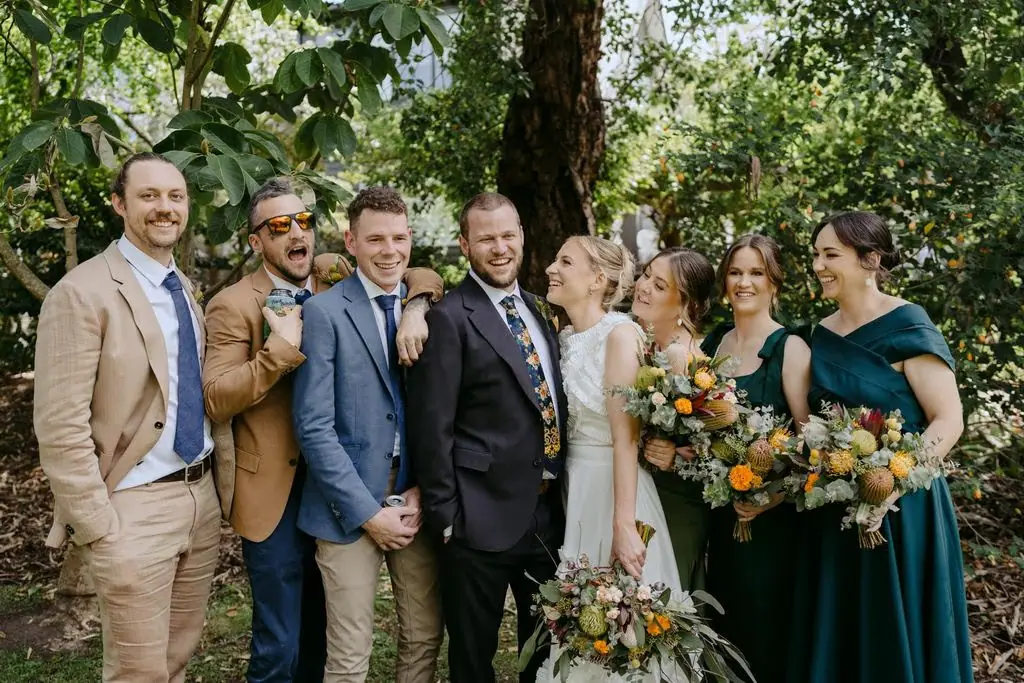 Wedding party standing together among the trees
