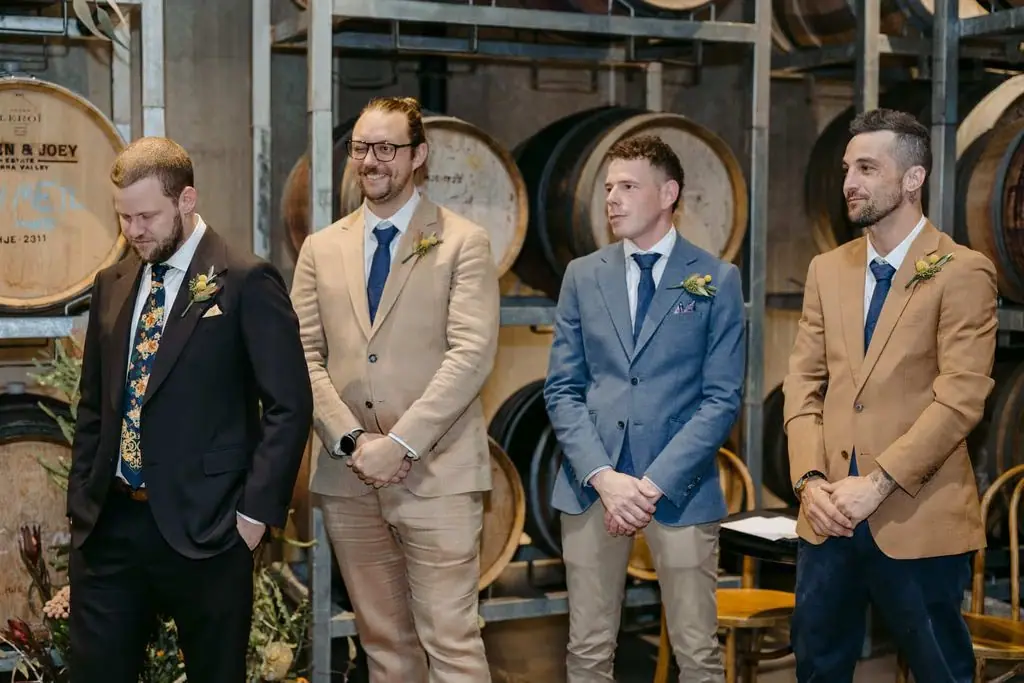 Groomsmen standing in front of wine barrels