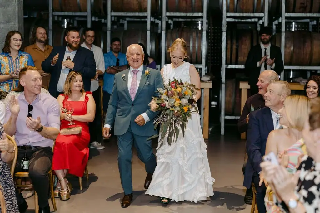 Bride walking into the ceremony beside an older guest