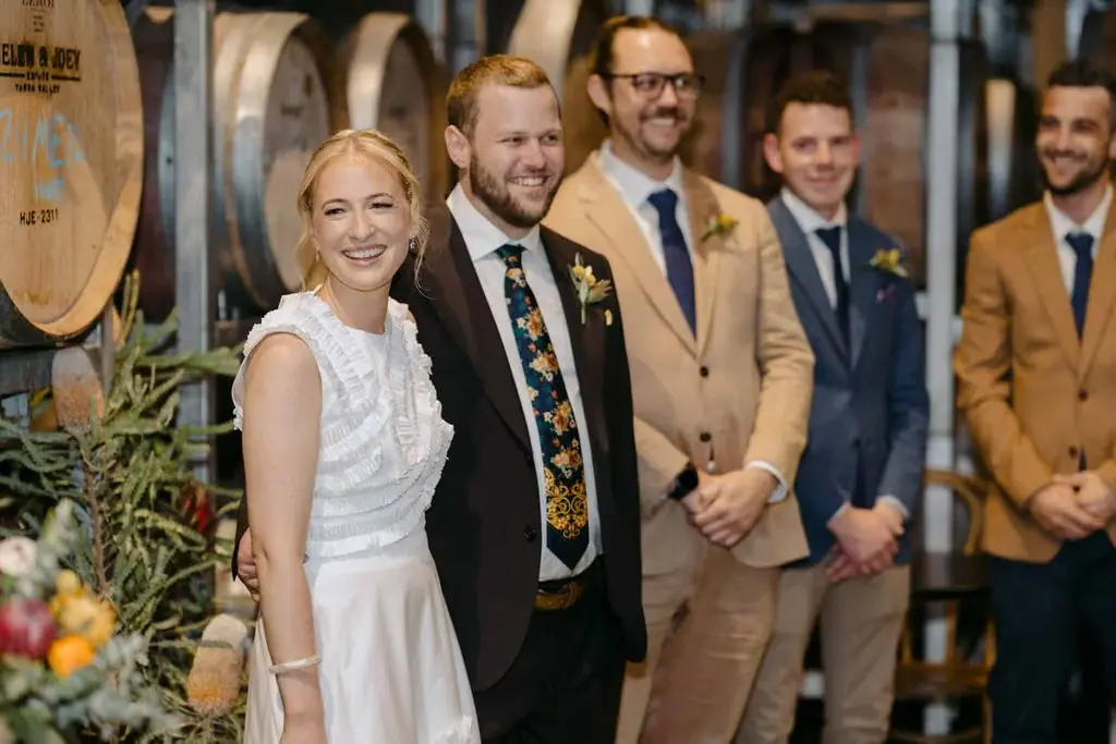 Couple standing with the wedding party in the barrel room