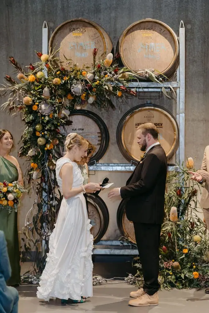 Couple exchanging rings beside the floral ceremony display