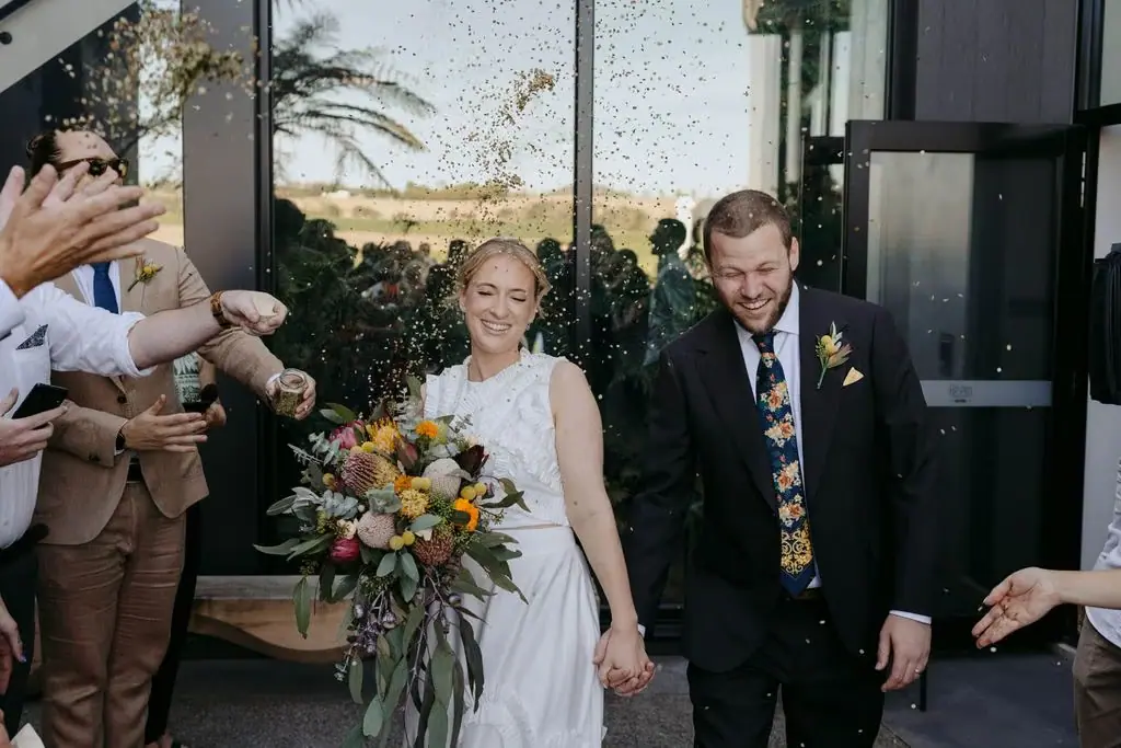 Couple walking out of the ceremony through smiling guests